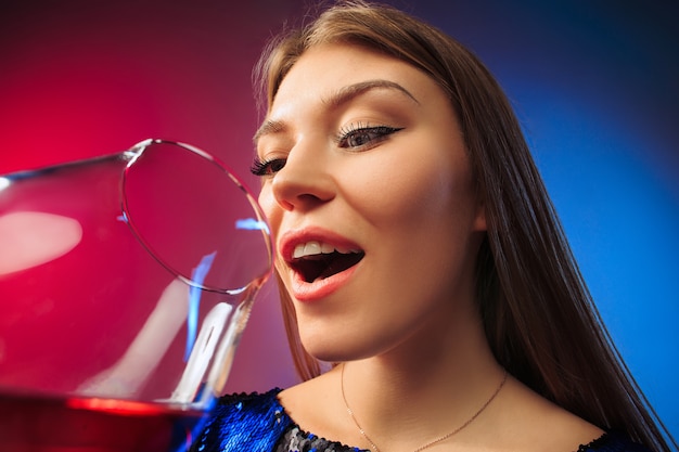 sorprendida joven en ropa de fiesta posando con copa de vino. Cara linda mujer emocional.