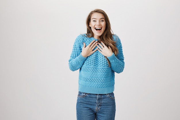 Sorprendida mujer emocionada tomar las manos en el pecho y sonriendo