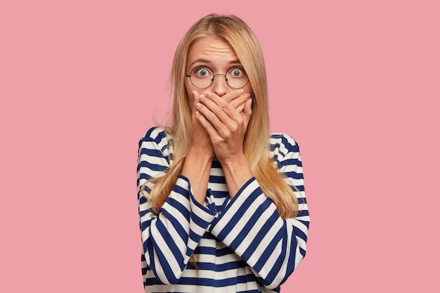 Foto gratuita sorprendida mujer rubia posando contra la pared rosa