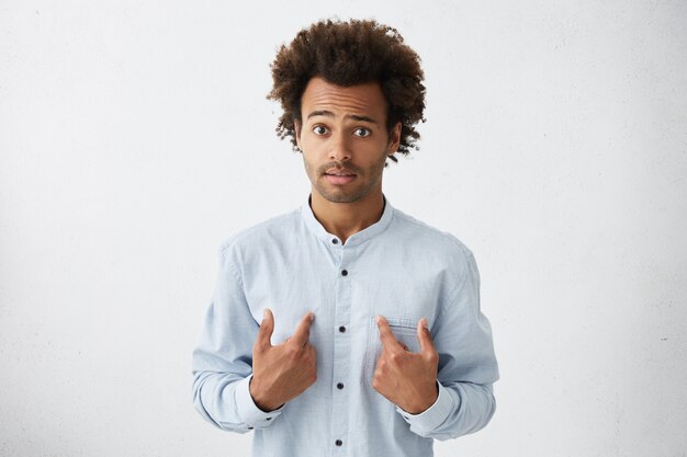 Sorprendido apuesto hombre de negocios africano en elegante camisa blanca apuntando a sí mismo