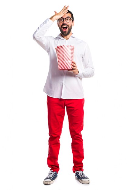 Sorprendido hombre guapo con gafas comiendo palomitas