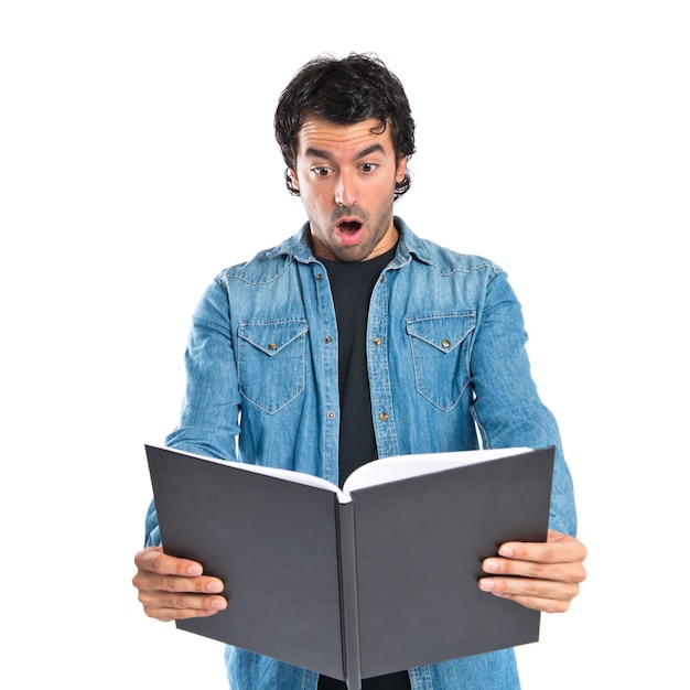 Sorprendido hombre leyendo un libro sobre fondo blanco