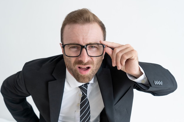 Sorprendido jefe mirando a la cámara a través de gafas. Sorprendente concepto de noticias de negocios.