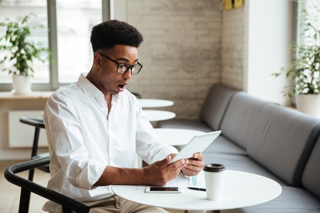 Sorprendido joven africano sentado coworking