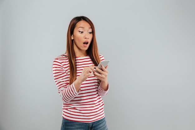 Sorprendido joven asiática chateando por teléfono