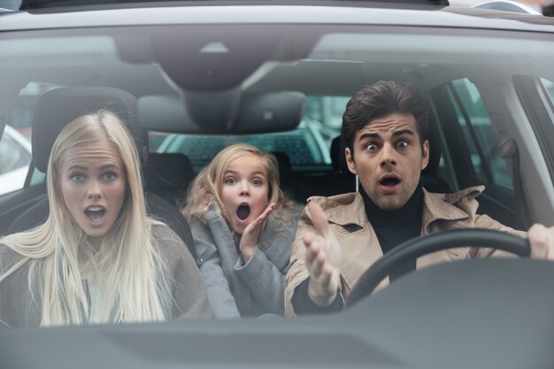 Sorprendido joven asustado sentado en coche con familia