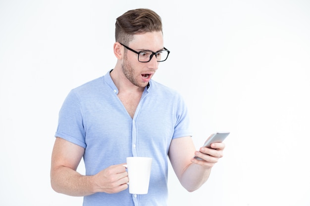 Sorprendido joven en gafas con teléfono inteligente