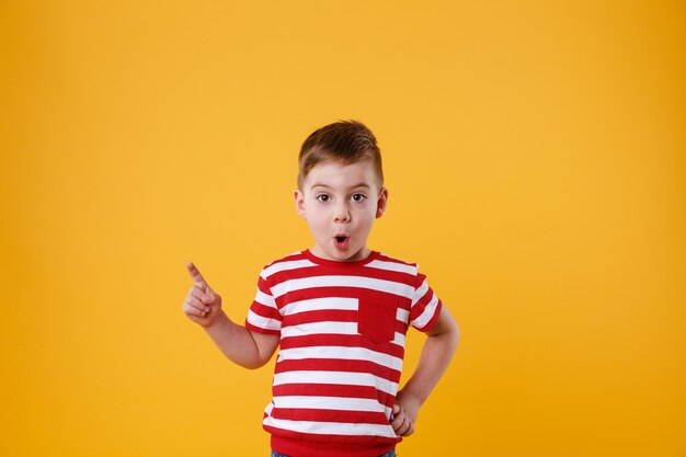 Sorprendido niño parado y señalando con el dedo