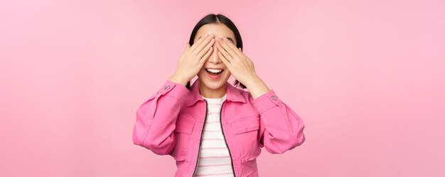 Sorpresa y celebración Retrato de una chica asiática feliz que cierra los ojos esperando un regalo anticipando algo parado con los ojos vendados contra el fondo del estudio Copiar espacio