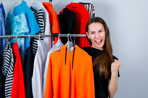 Sostener a la chica de la sudadera se siente feliz y levanta el puño en el fondo de la ropa