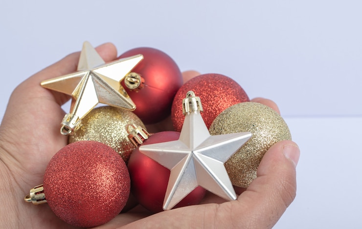 Foto gratuito sosteniendo bolas de árbol de navidad y estrellas en la mano