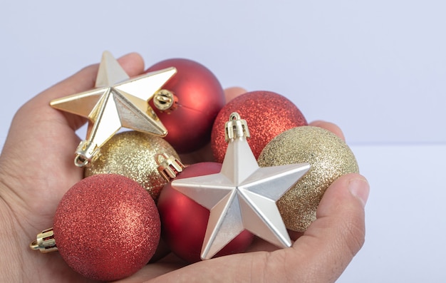 Sosteniendo bolas de árbol de Navidad y estrellas en la mano