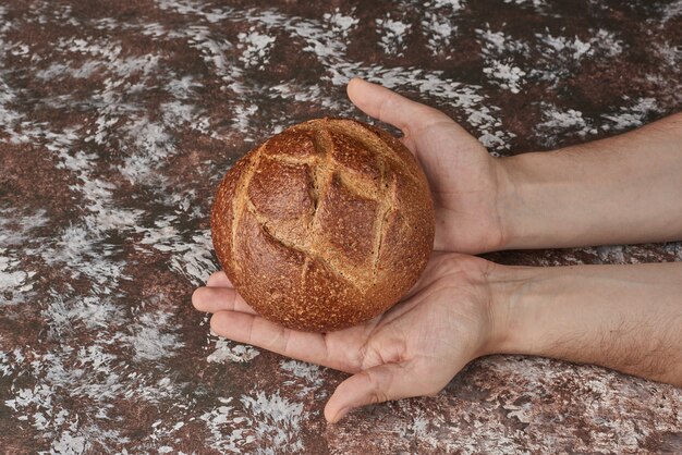 Sosteniendo un bollo de pan en la mano.