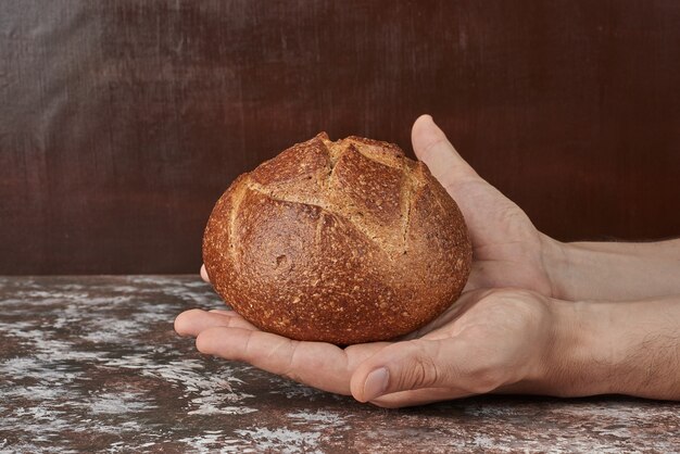 Sosteniendo un bollo de pan en la mano.