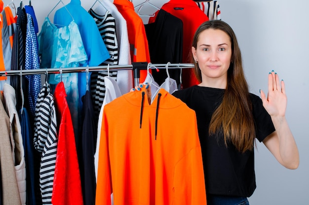 Sosteniendo a la chica de la camiseta está mostrando un gesto de hola en el fondo de la ropa