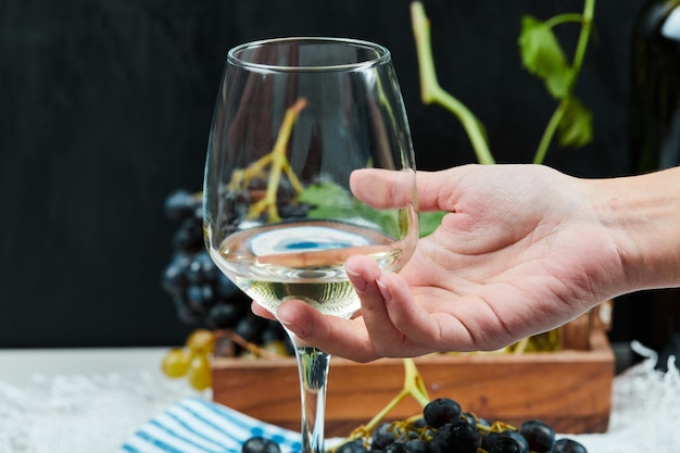 Sosteniendo una copa de vino blanco en la mano.