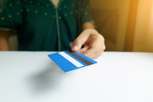 Sosteniendo y dando la tarjeta de crédito. Compras en línea, negocios en línea