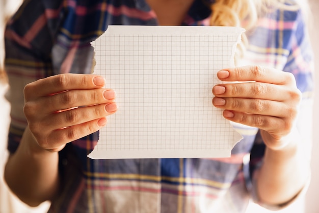 Sosteniendo hojas vacías. Cerca de manos femeninas caucásicas, trabajando en la oficina. Concepto de negocio, finanzas, trabajo, compras en línea o ventas. Copyspace. Freelance en educación, comunicación.