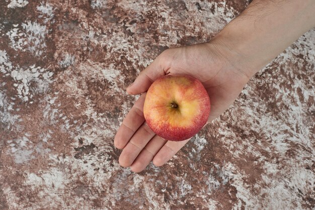 Sosteniendo una manzana amarilla en la mano.