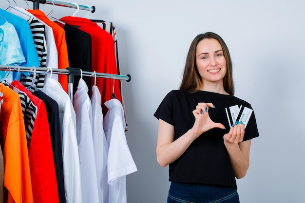 Sosteniendo tarjetas de crédito chica si mostrando gesto de tamaño en el fondo de la ropa