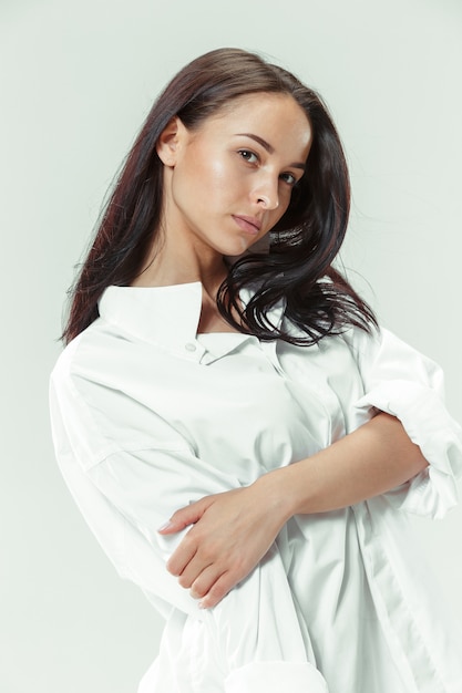 Soy joven y bonita. Retrato de hermosa niña morena en estudio gris