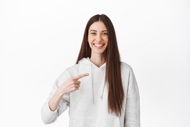 Soy quien necesitas Una mujer sonriente y segura de sí misma señalándose a sí misma elíjame fanfarroneando quiere participar nominarla de pie sobre fondo blanco