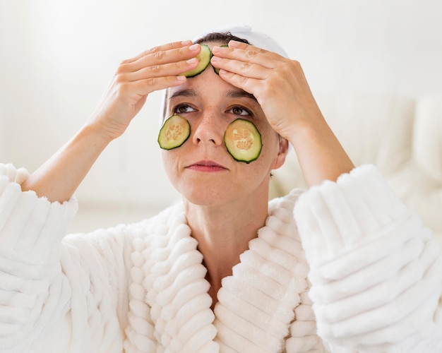 Spa en casa mujer aplicando rodajas naturales de pepinos en la cara