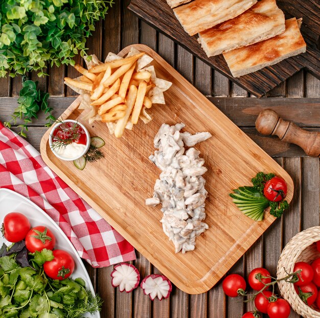 Stroganoff de ternera con papas fritas sobre tabla de madera