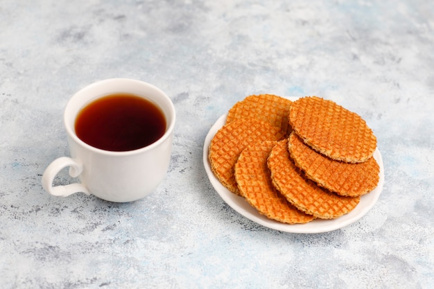 Stroopwafels, gofres holandeses de caramelo con té o café y miel sobre hormigón