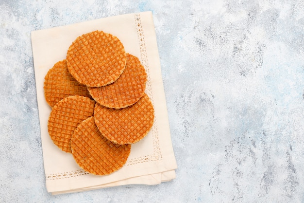 Stroopwafels, gofres holandeses de caramelo con té o café y miel sobre hormigón