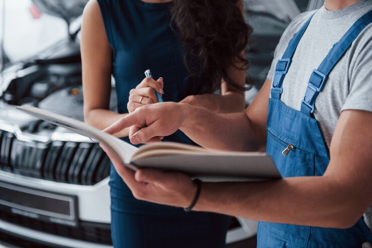 Foto gratuito su firma por favor. mujer en el salón del automóvil con empleado en uniforme azul tomando su auto reparado