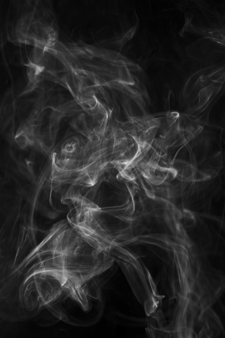 Foto gratuito suavemente soplando humo extendido contra el fondo negro