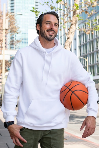 Foto gratuita sudadera con capucha de un hombre con baloncesto en la ciudad.