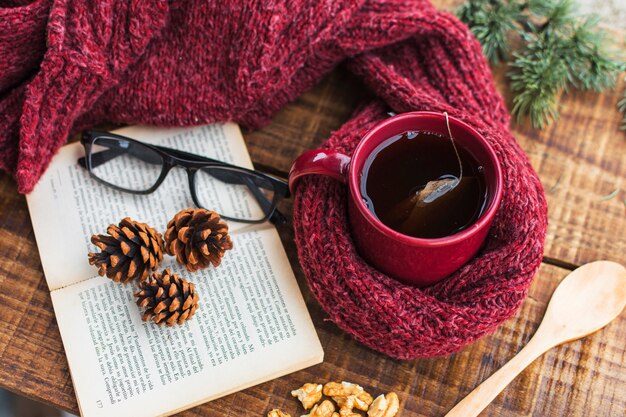 Suéter y té cerca de libro y gafas