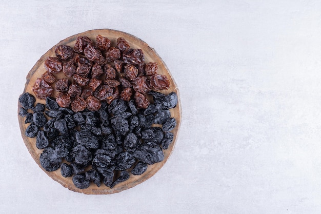 Sultana negra seca y cerezas en un plato de madera. Foto de alta calidad