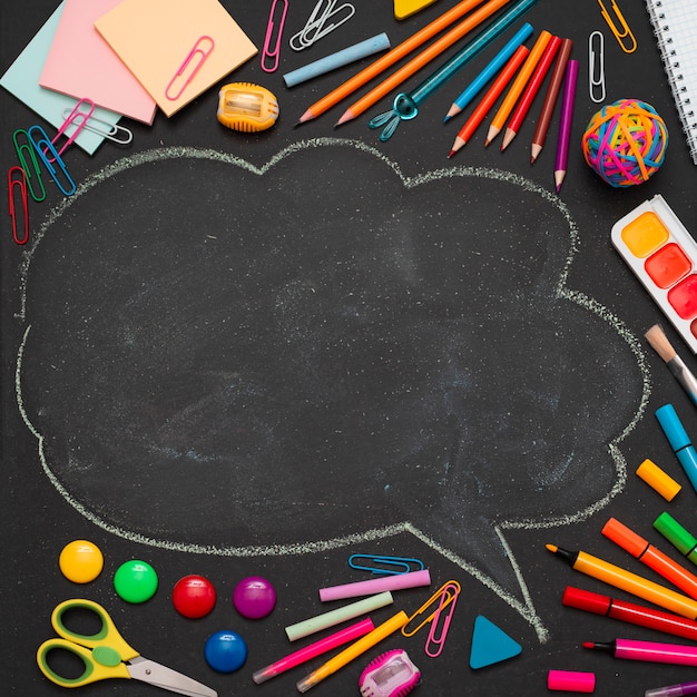 Suministros escolares multicolores, lápices y una nube dibujada con espacio para copiar texto.