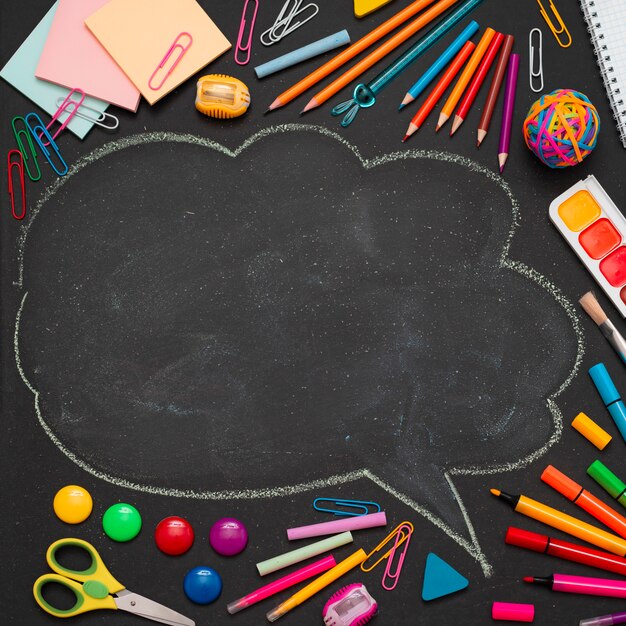 Suministros escolares multicolores, lápices y una nube dibujada con espacio para copiar texto.