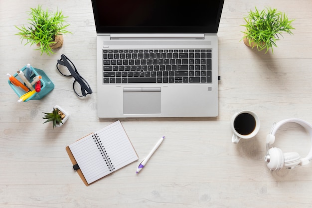 Suministros de oficina con laptop; Taza de café y auriculares en el escritorio de madera