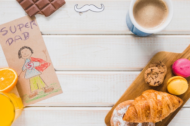 Foto gratuita súper papá dibujando cerca de café y pastelería