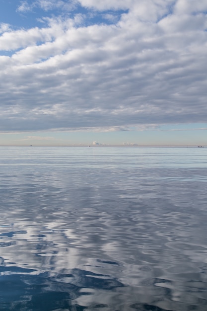 Superficie del agua que refleja el cielo nublado blanco