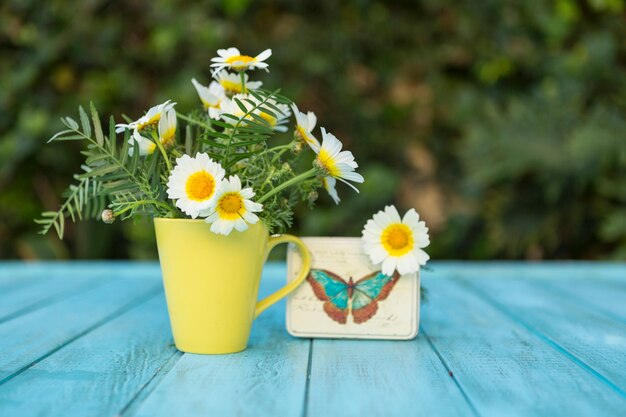 Superficie azul con margaritas bonitas, caja metálica y taza