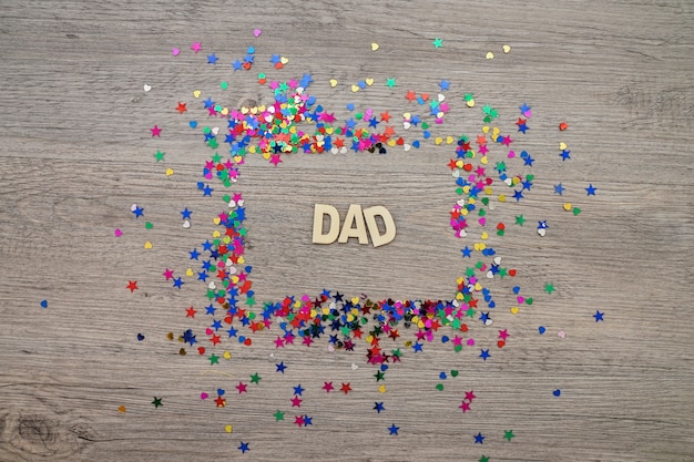 Foto gratuita superficie de mader con marco de confeti y la palabra papá