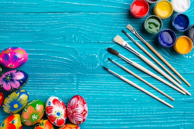 Foto gratuita superficie de madera azul con huevos de pascua y pinceles