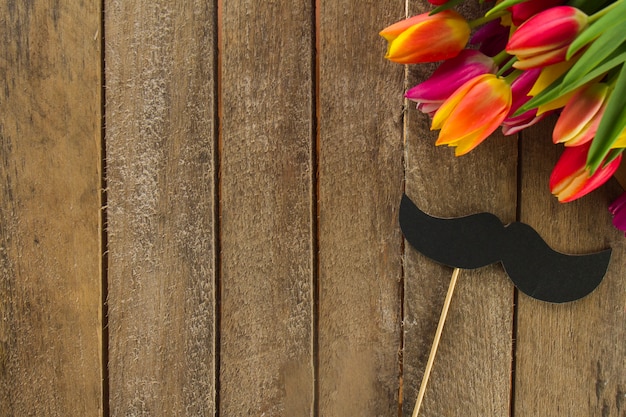 Foto gratuita superficie de madera con bigote y flores de colores