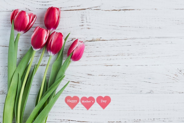 Superficie de madera blanca con tulipanes y corazones para el día de la madre