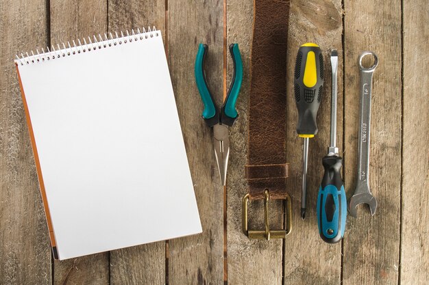 Superficie de madera con cuaderno en blanco y herramientas decorativas