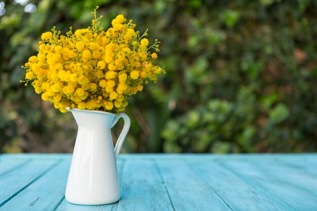 Superficie de madera con flores en un florero de porcelana