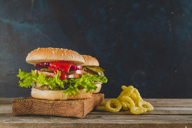 Superficie de madera con hamburguesas y aros de cebolla