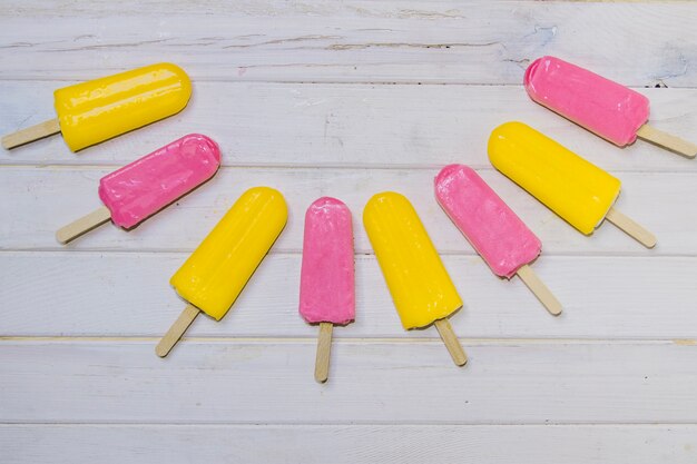 Superficie de madera con helados rosas y amarillos