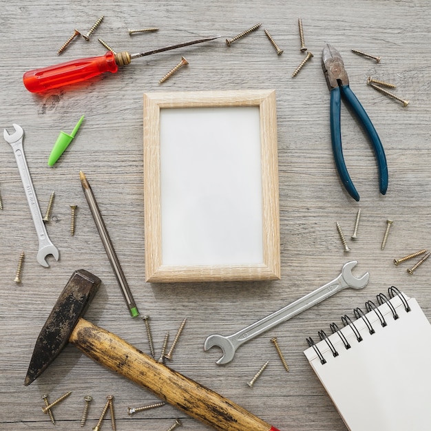 Superficie de madera con marco, cuaderno y herramientas